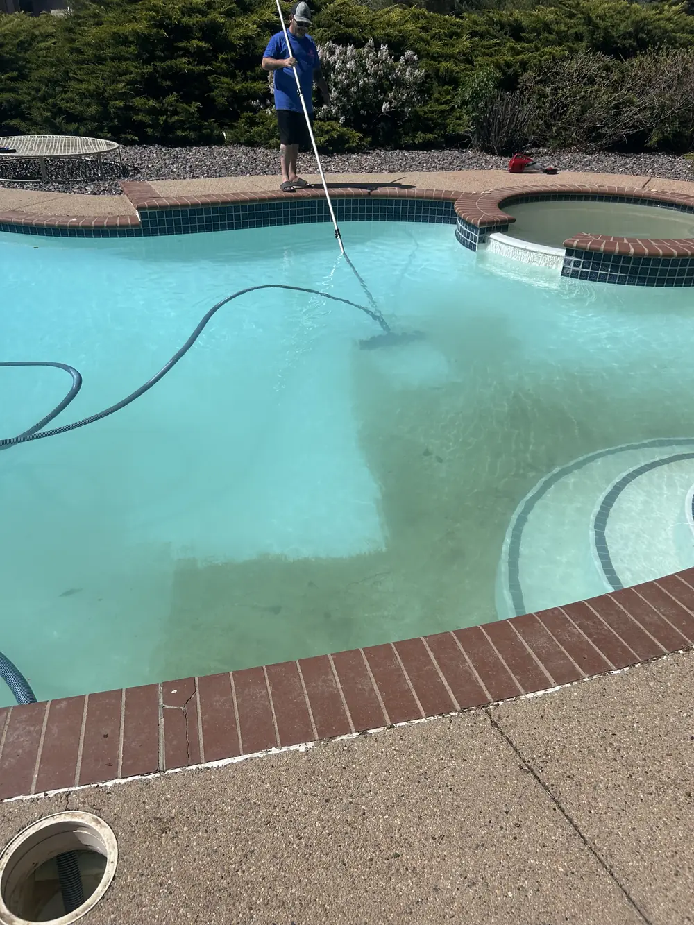 Joel vacuuming a freeform pool with raised spa in Broomfield, CO