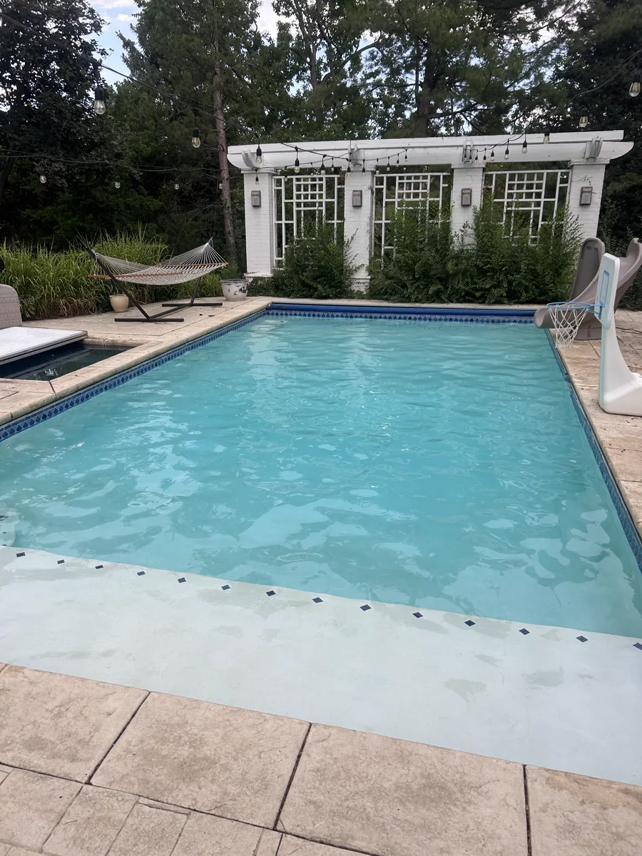 Clear backyard pool with white pergola and tanning ledge serviced by Pyle's in Denver, CO
