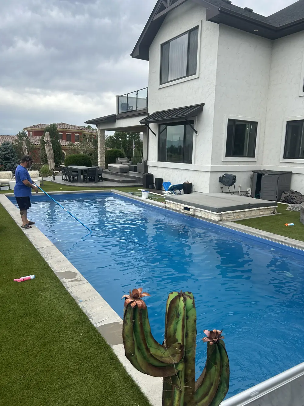 Joel skimming a modern rectangular pool behind a luxury home in Erie, CO