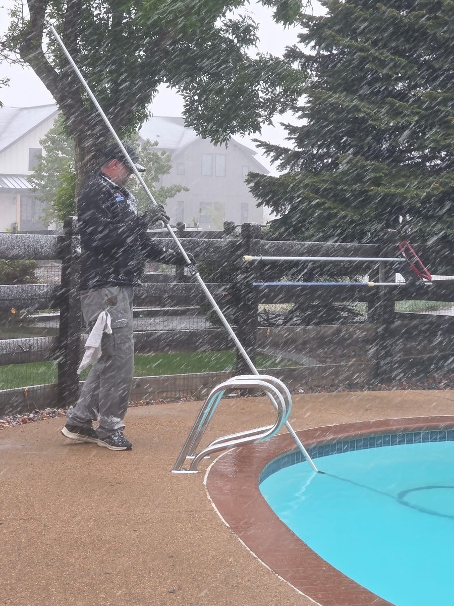 Pool technician servicing a pool during a heavy spring snowstorm in Denver metro