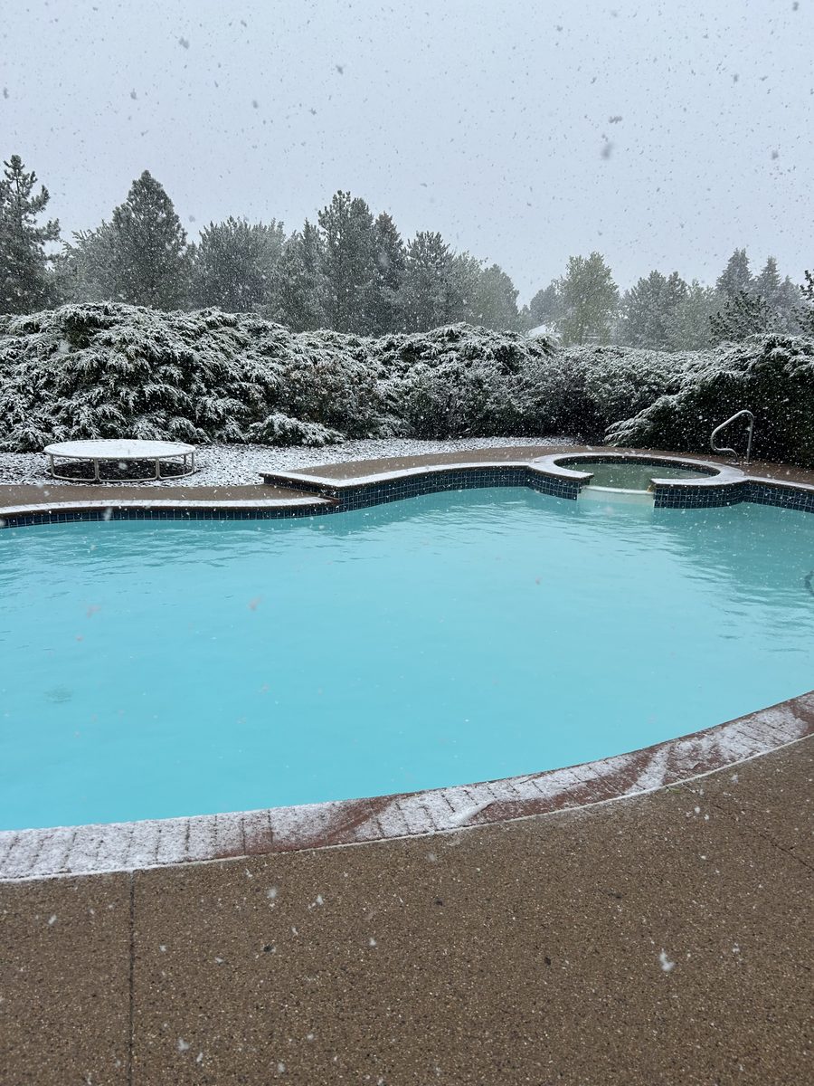 Crystal clear pool with spa during Colorado spring snowfall
