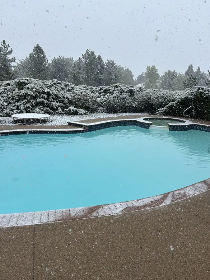 Crystal clear pool with spa during Colorado spring snowfall