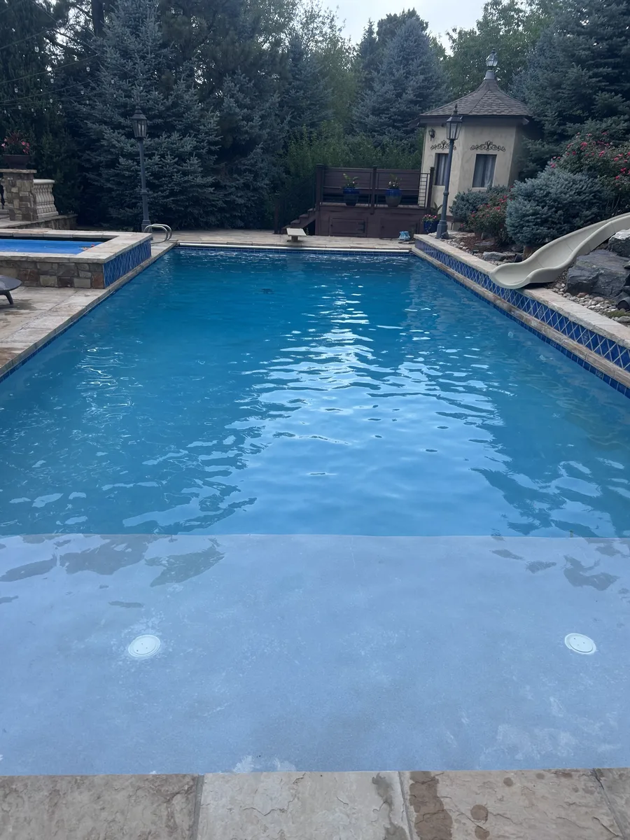 Clear blue pool with slide and attached hot tub spa serviced in Greenwood Village, CO