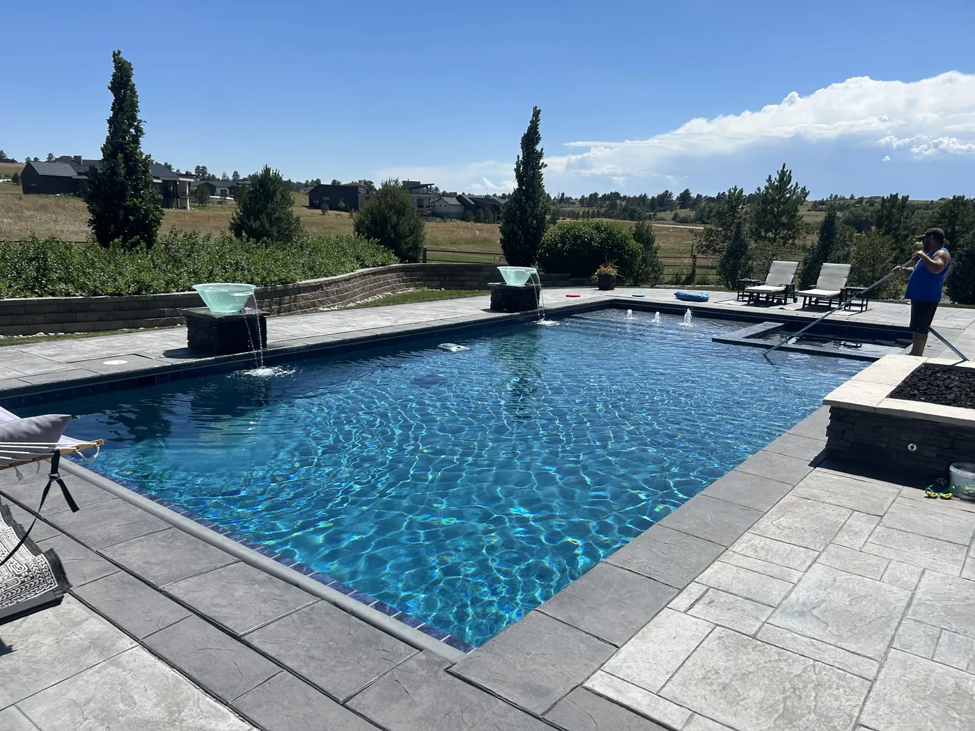 Rectangular pool with fire bowls and stone patio serviced by Pyle's in Parker, CO