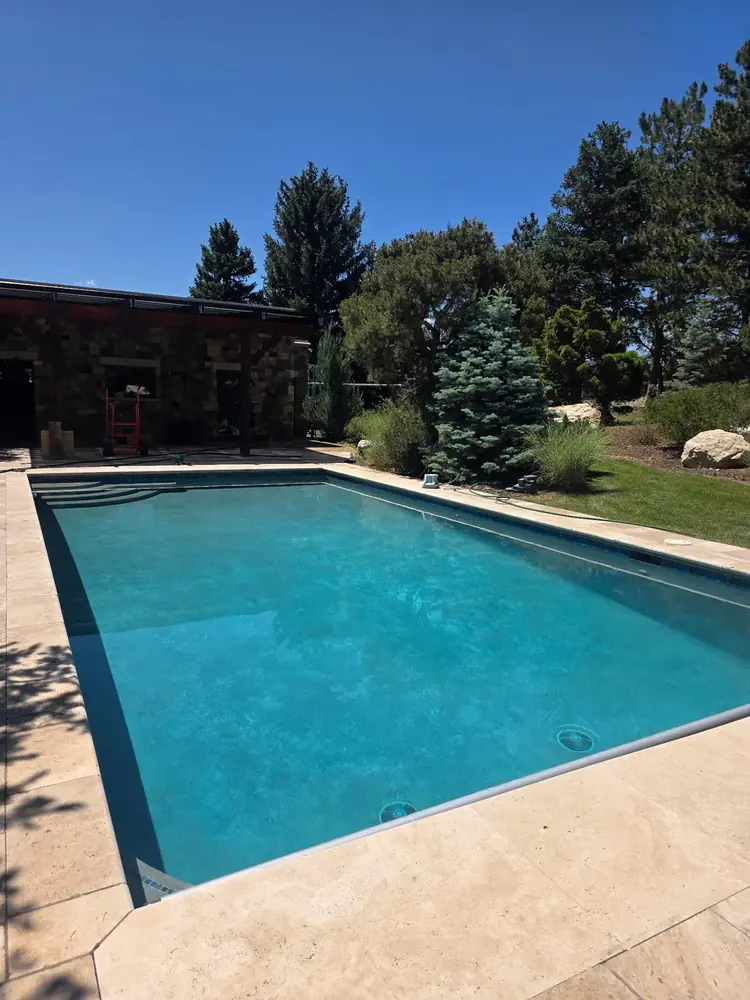 Sparkling clean backyard pool beside a stone home in Metro Denver, serviced by Pyle's Pool & Spa Specialists