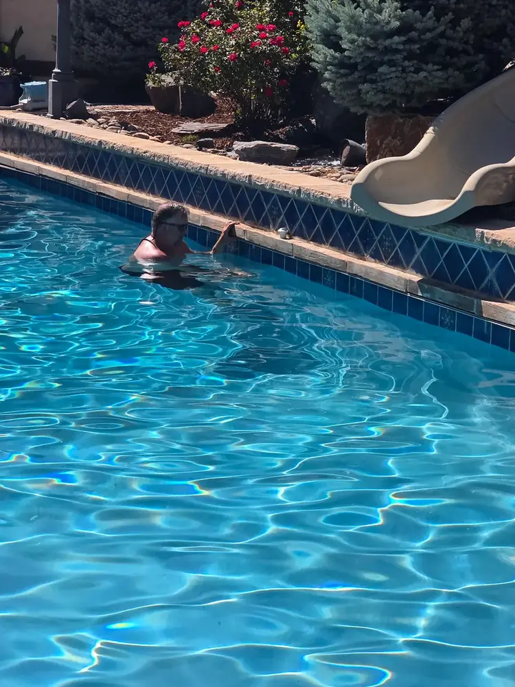 Pyle's technician brushing the waterline tile of a Denver pool to prevent algae and scale buildup