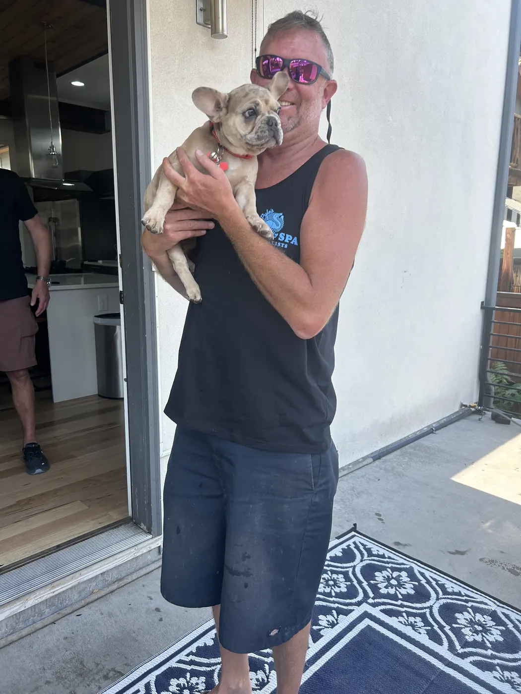 Pyle's Pool & Spa team member holding a customer's French bulldog puppy
