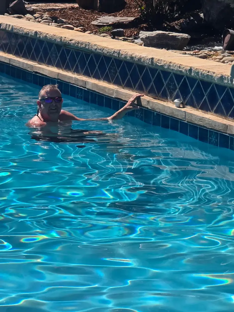 Joel, owner of Pyle's Pool & Spa Specialists, in a customer's pool checking water and tile line